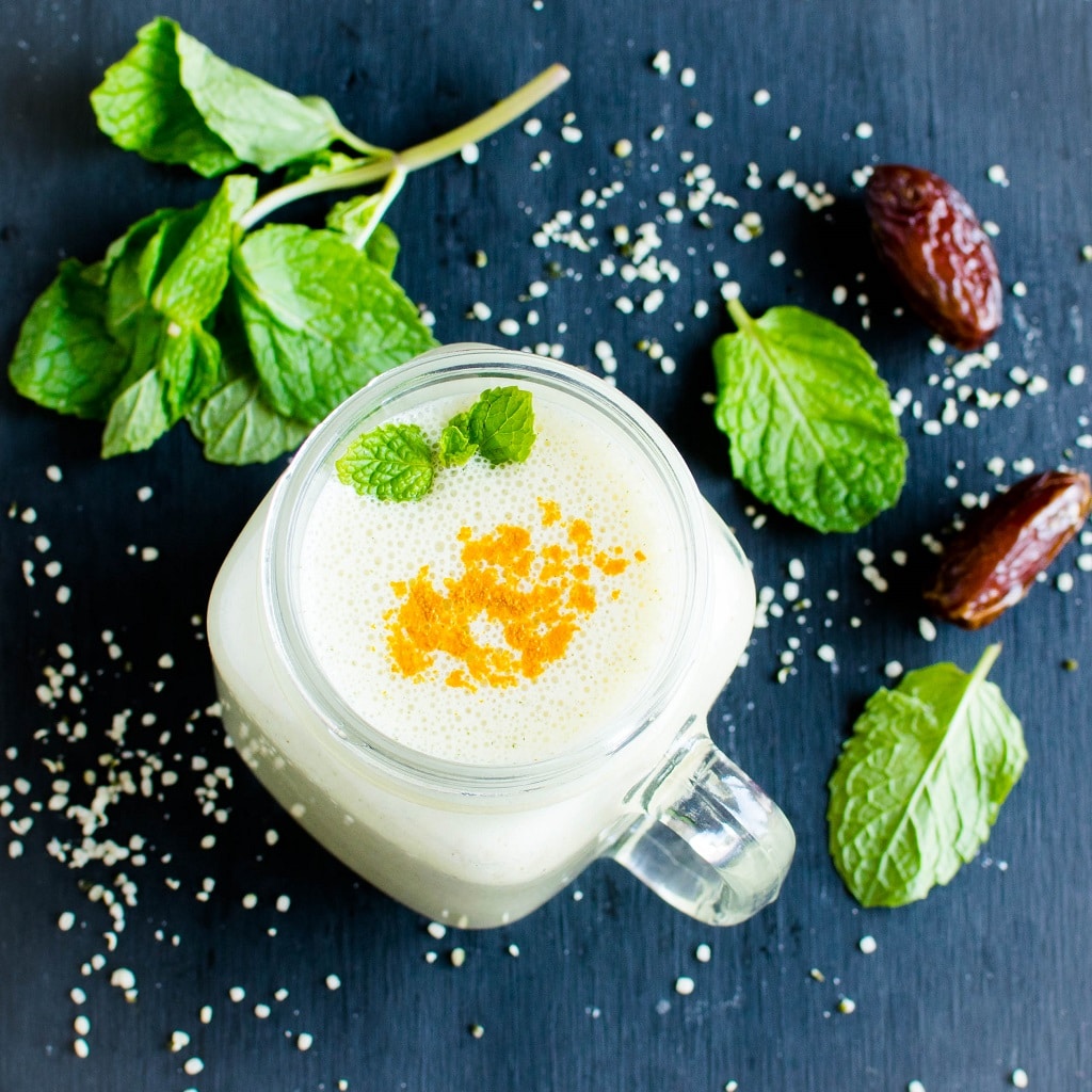 The top view of turmeric mint protein smoothie is shown in this image and the raw ingredients are displayed as the props | kiipfit.com