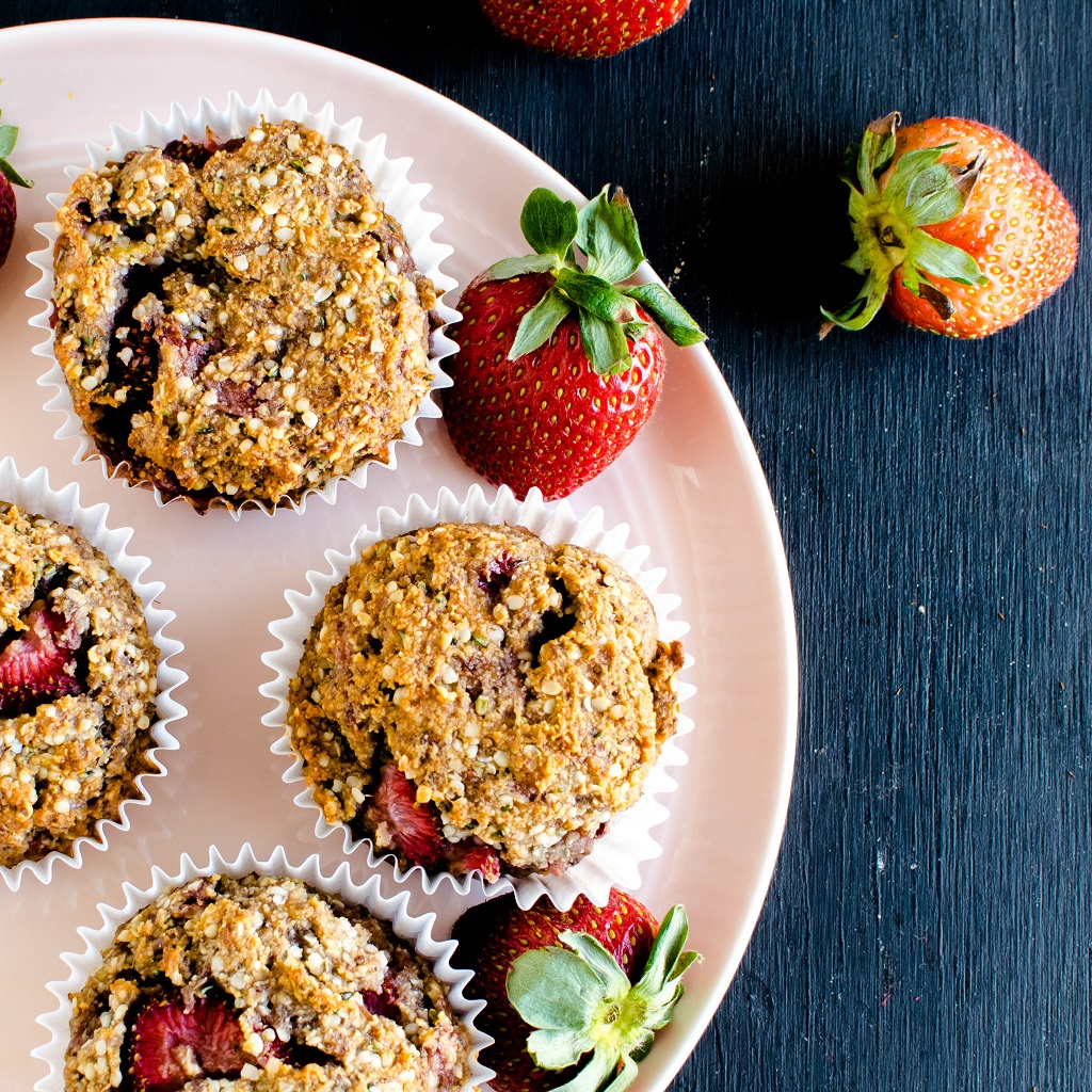 Strawberry Jam Vegan Protein Muffins are shown on a pink colcored round plate with fresh strawberries as the prop | kiipfit.com