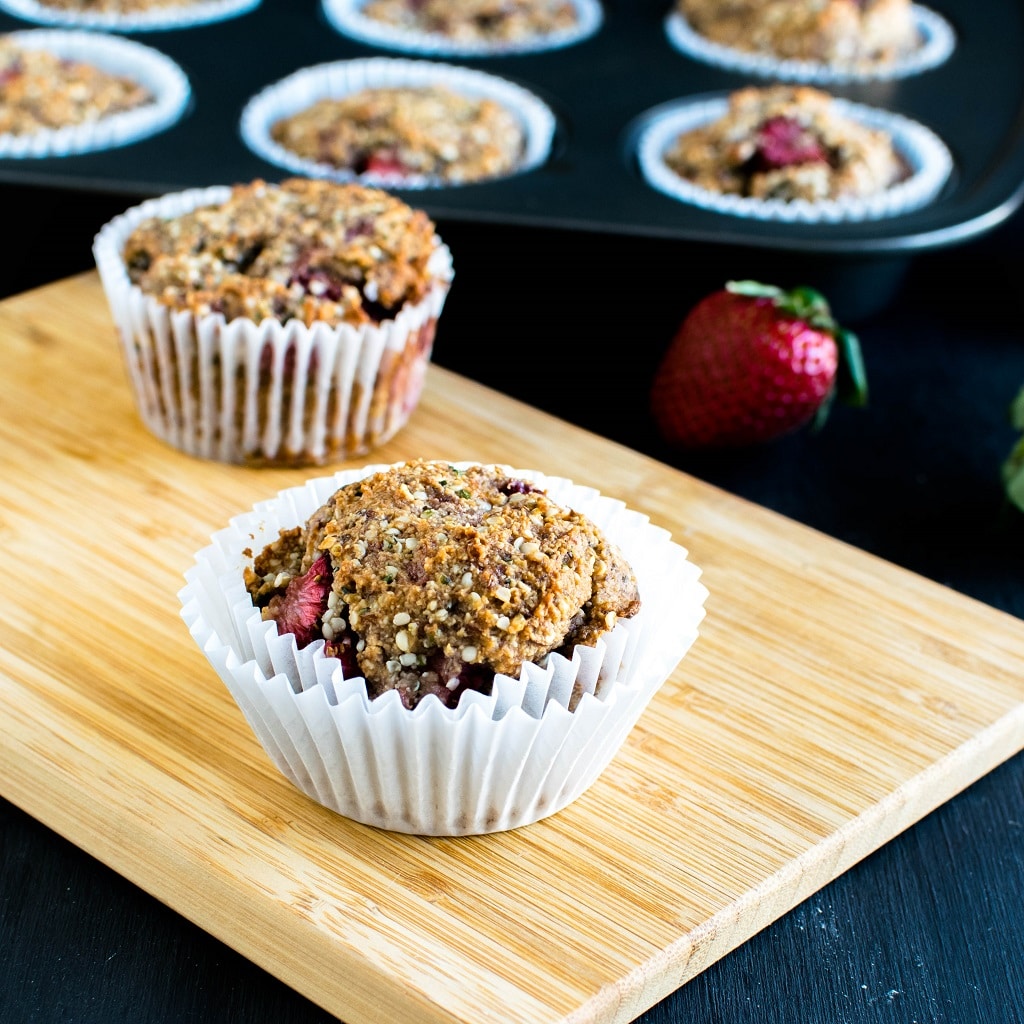 A wooden board is shown with strawberry jam vegan protein muffins and loaded muffin tray at the background | kiipfit.com 